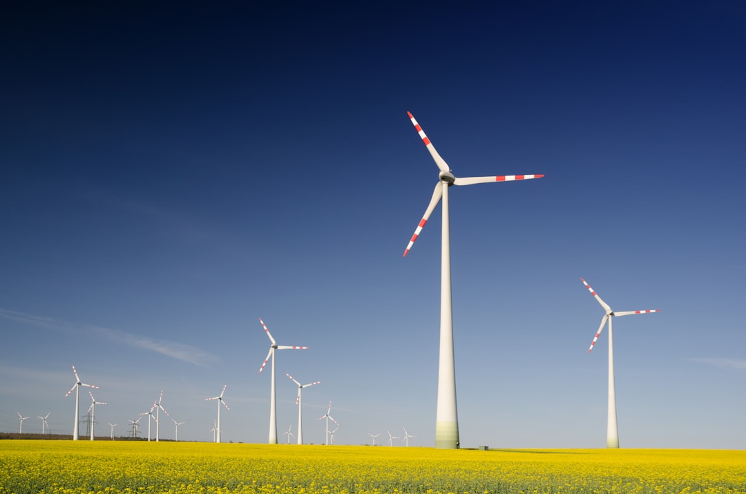Wind turbines in a vibrant yellow field under a clear blue sky, symbolizing energy transformation and positive energy protection.